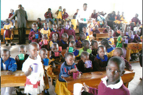 Lapsia kahvimukit kädessä koululuokassa.