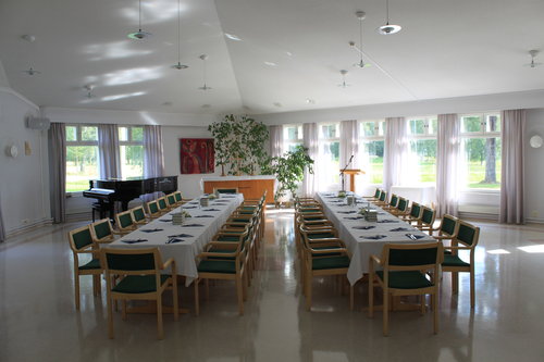 Seurakuntasalissa sisällä kaksi pöytäriviä katettuina valkoisin pöytäliinoin ruokailuun.